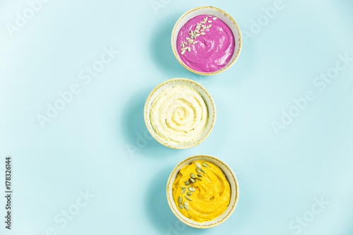 Snacks in the form of sauces from carrots, beets and hummus from chickpeas. in bowls on a contrasting blue background