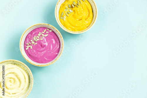 Snacks in the form of sauces from carrots, beets and hummus from chickpeas. in bowls on a contrasting blue background