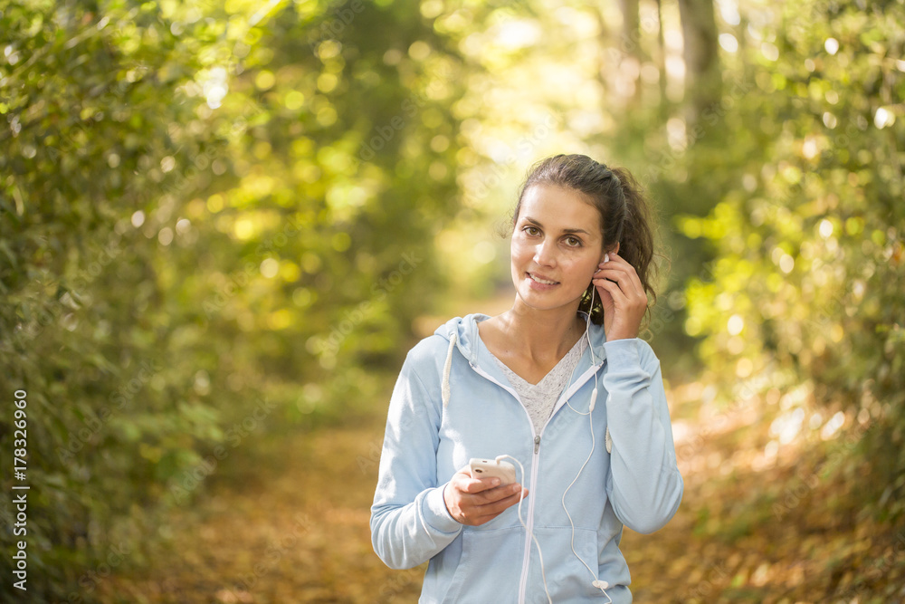 woman using smartphone after running on forest in autumn woman using smartphone after running on forest in autumn