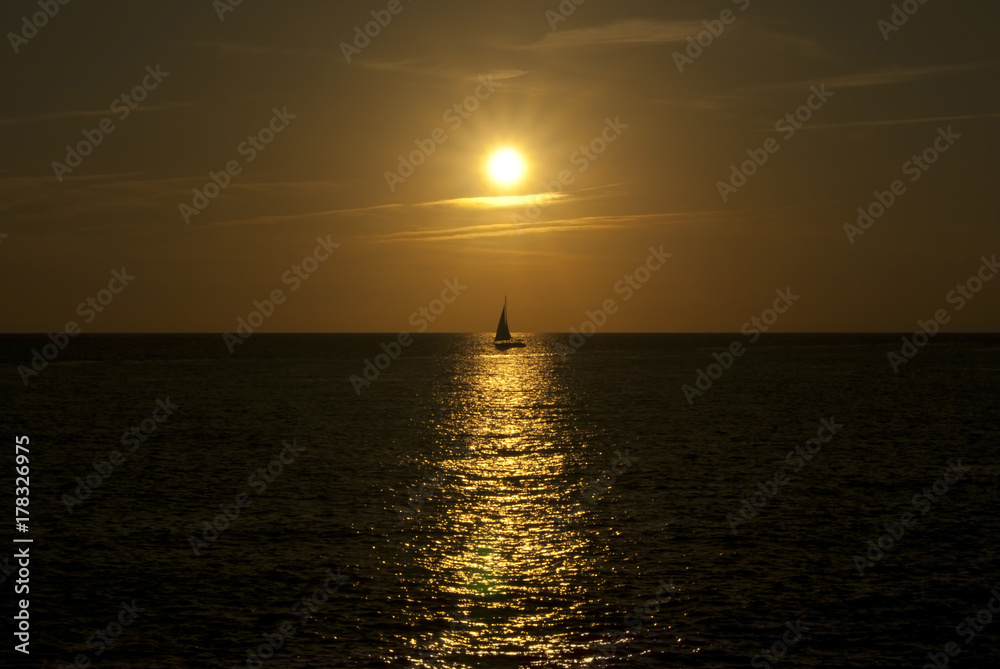 sunset or sunrise over the sea horizon, the sunny path and the silhouette of a sailboat sunset or sunrise over the sea horizon, the sunny path and the silhouette of a sailboat