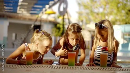 Dear children of successful parents in the pool children with a cocktail in hand relaxing in the pool