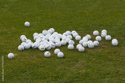 Assorted golf balls on the green grass photo