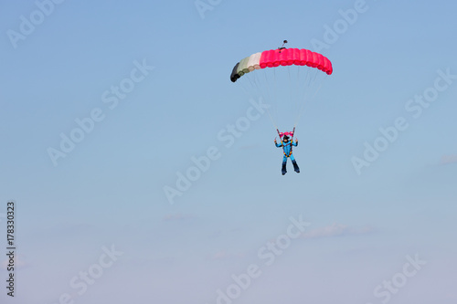 skydiver on pink parachute on background blue sky