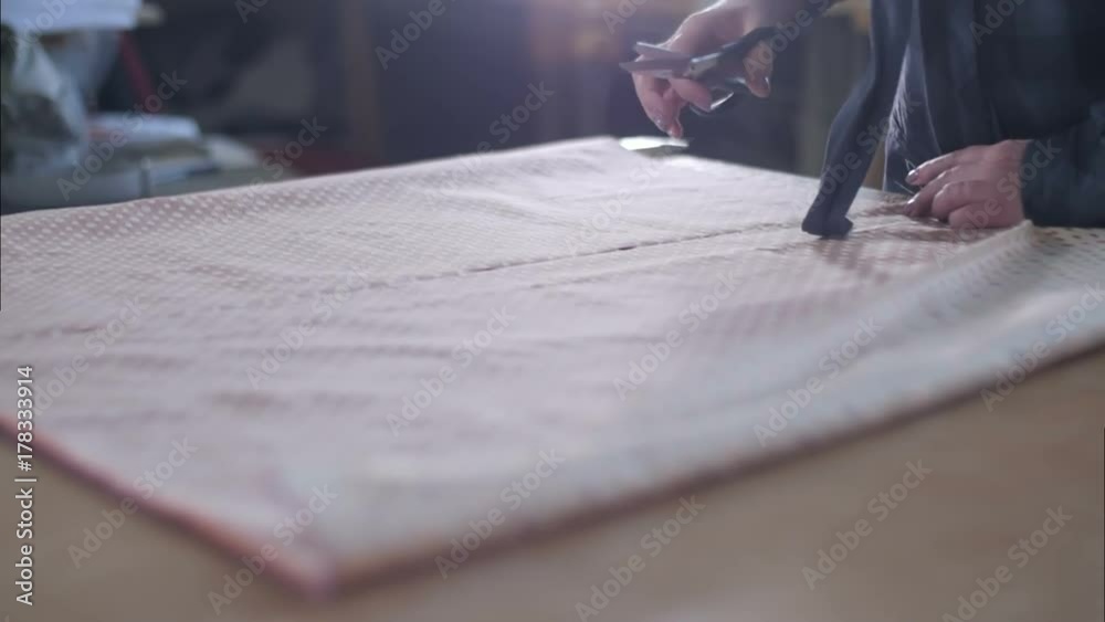 Tailor working at studio cutting fabric, detail of hand with scissors Tailor working at studio cutting fabric, detail of hand with scissors