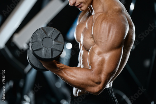 Handsome model young man training arms in gym