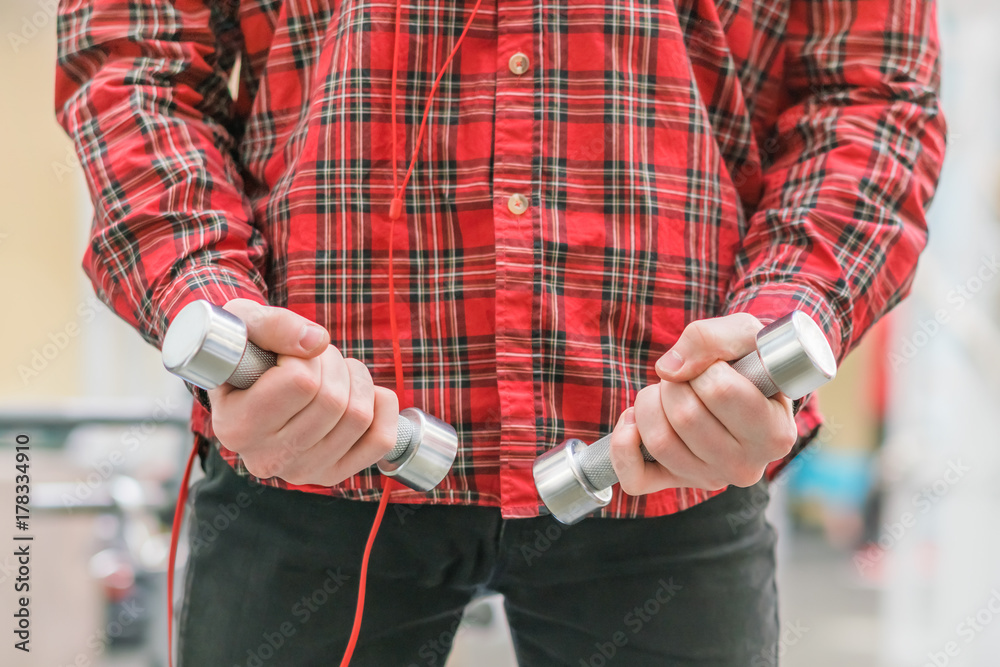 Man in a red checkered shirt with small dumbbells in his hands