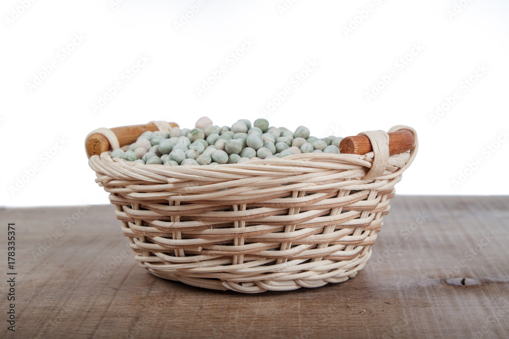 peas in a wicker basket on a wooden table