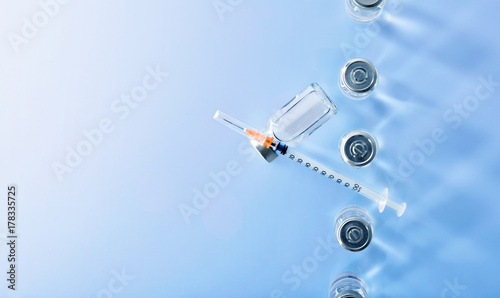 Row of vials and syringe on blue table top view
