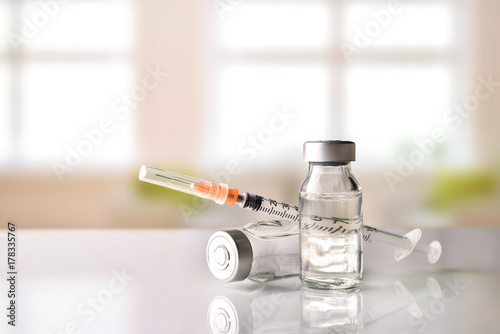 Vials and syringe on white table with background windows