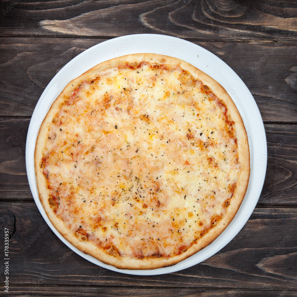 Pizza margarita on a white plate, and a black wooden table Pizza margarita on a white plate, and a black wooden table