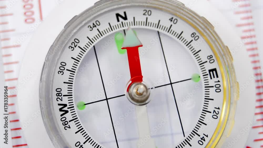 Close up of a magnetic directional compass with the needle swinging and then pointing North. Close up of a magnetic directional compass with the needle swinging and then pointing North.