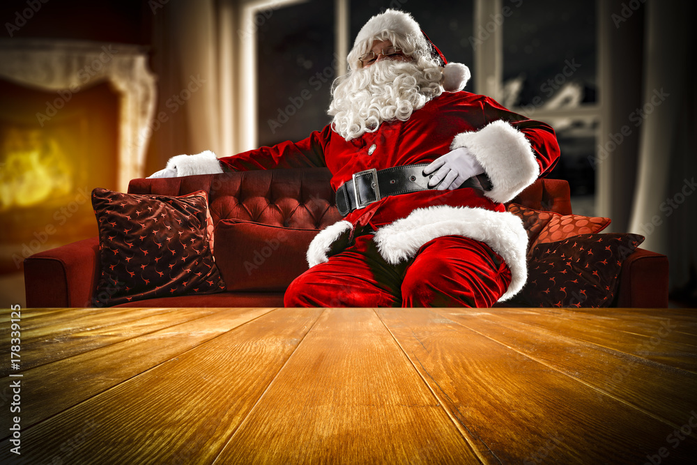 Obraz premium santa claus on sofa and wooden table place 