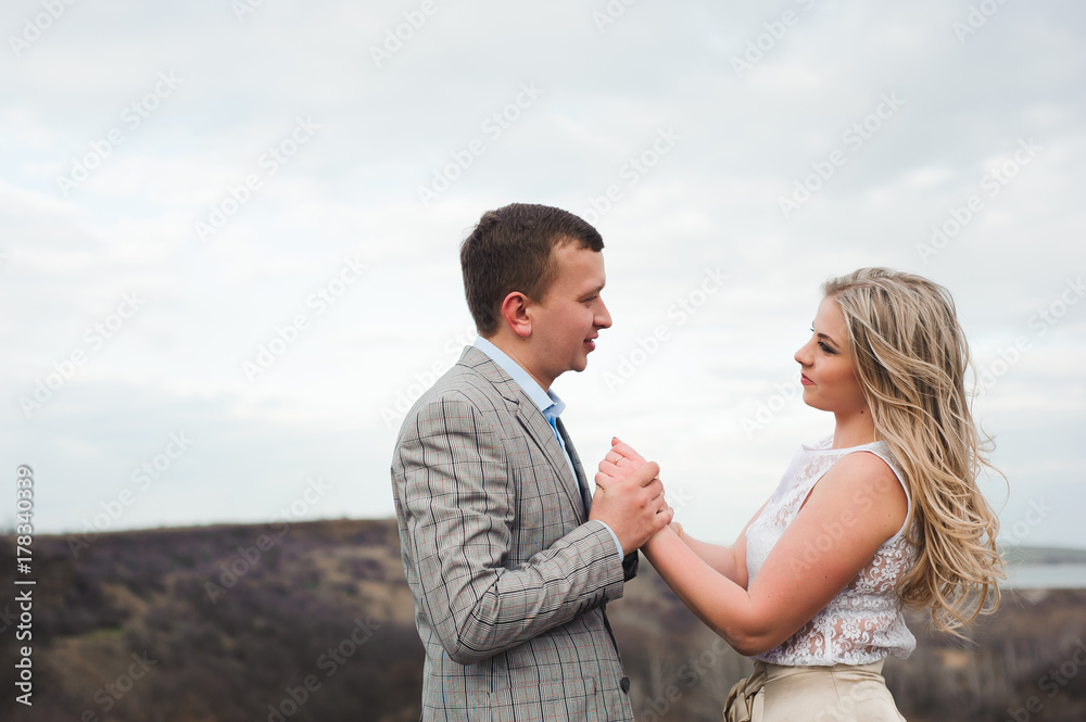 happy young couple hugging on the edge of the mountain, in the background a very beautiful landscape