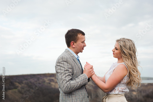 happy young couple hugging on the edge of the mountain, in the background a very beautiful landscape