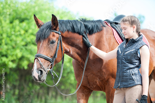 Young teenage girl tenderly looking at her favorite red horse © AnnaElizabeth