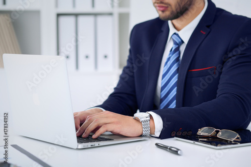 Businessman working by typing on laptop computer. Man's hands on notebook or business person at workplace. Employment  or start-up concept