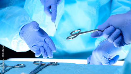 Surgeons hands holding surgical scissors and passing surgical equipment, close-up. Health care and veterinary concept