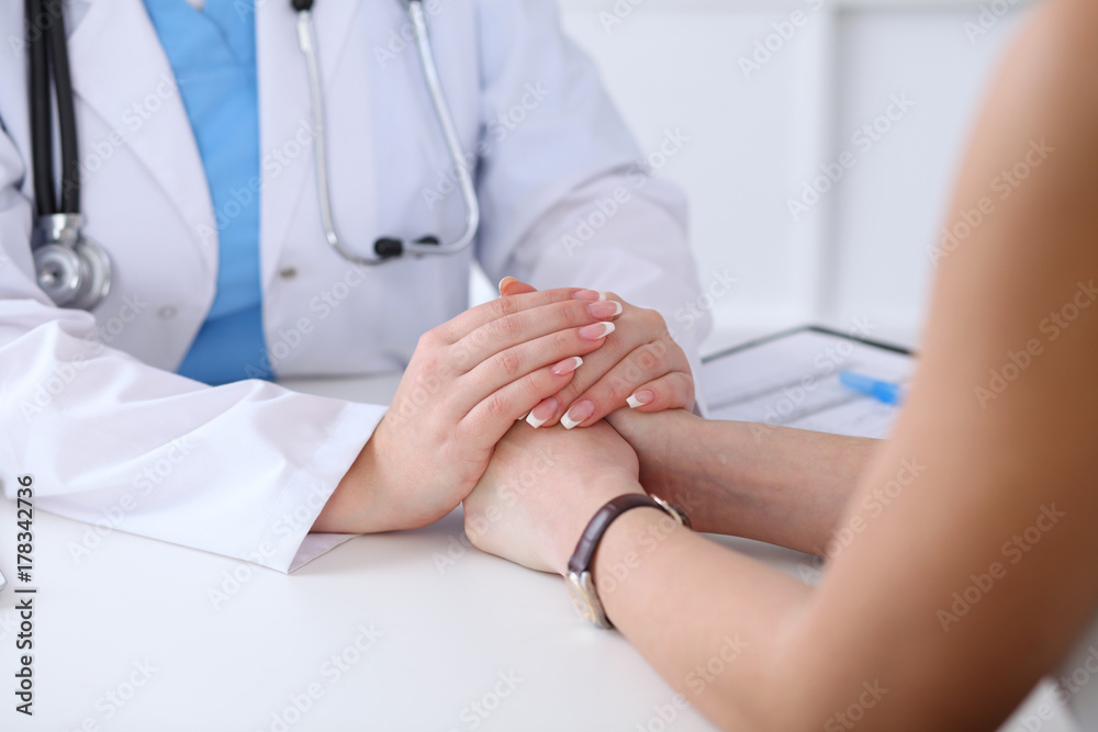 Close up of doctor hands reassuring her female patient