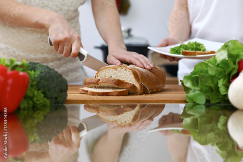 Close-up of human hands slicing bread in a kitchen. Friends having fun while cooking in the kitchen. Chef cook represent culinary masterclass