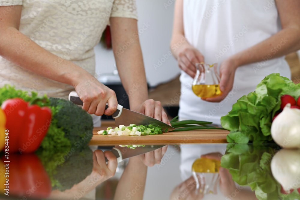 Close-up of  human hands  cooking in a kitchen. Friends having fun while preparing fresh salad. Vegetarian, healthy meal and friendship concept