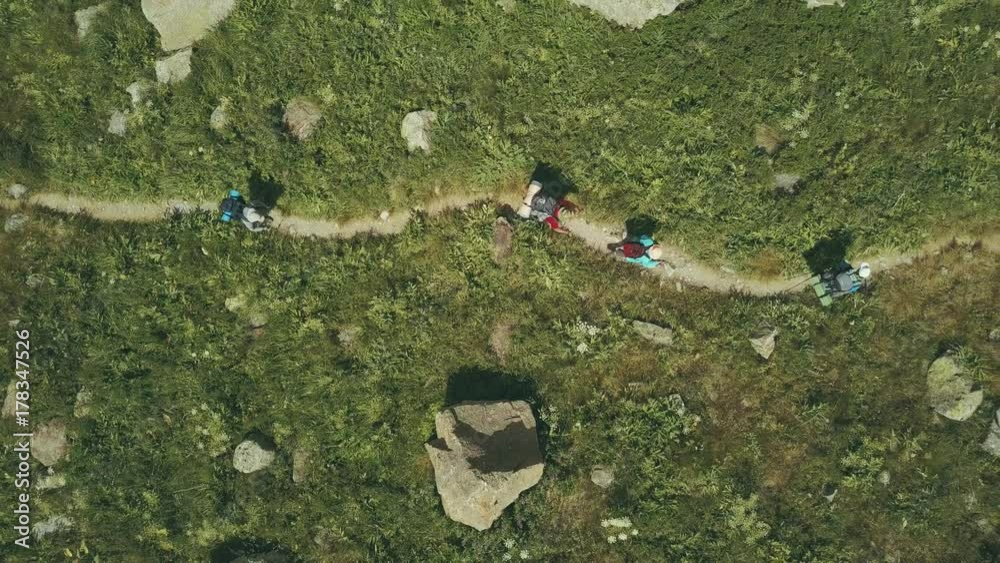 Aerial shooting from flying drone hiking group walking on mountain trail