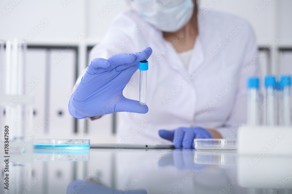 Close-up of professional female scientist in protective eyeglasses making experiment with reagents in laboratory. Medicine and research concept Close-up of professional female scientist in protective eyeglasses making experiment with reagents in laboratory. Medicine and research concept