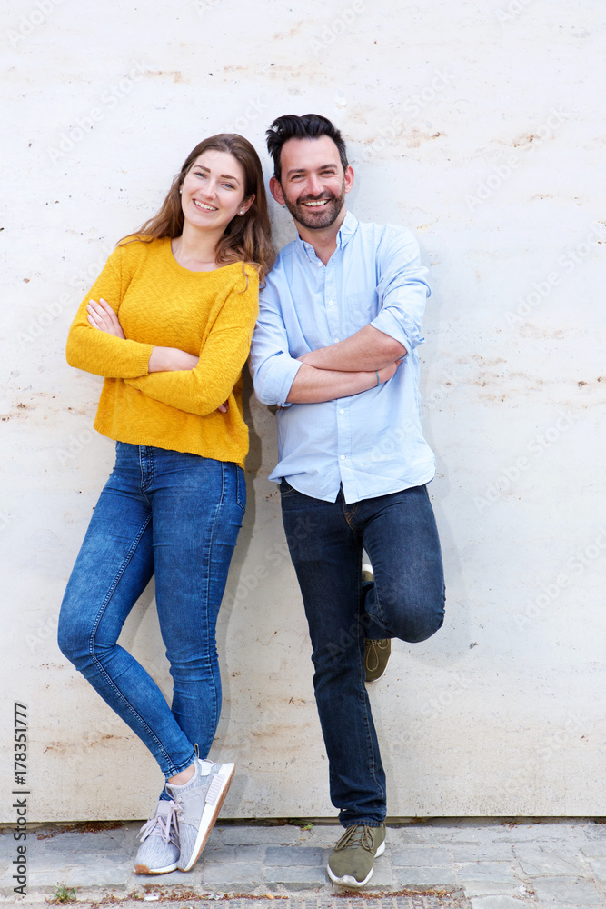 Portrait of happy couple posing together standing with arms crossed