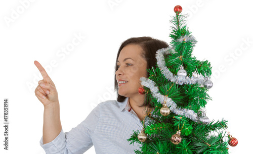 New Year Concept. Beautiful Woman hold Decorated Christmas Tree and Pointing Her Finger to Copy Space for Yourth Design photo