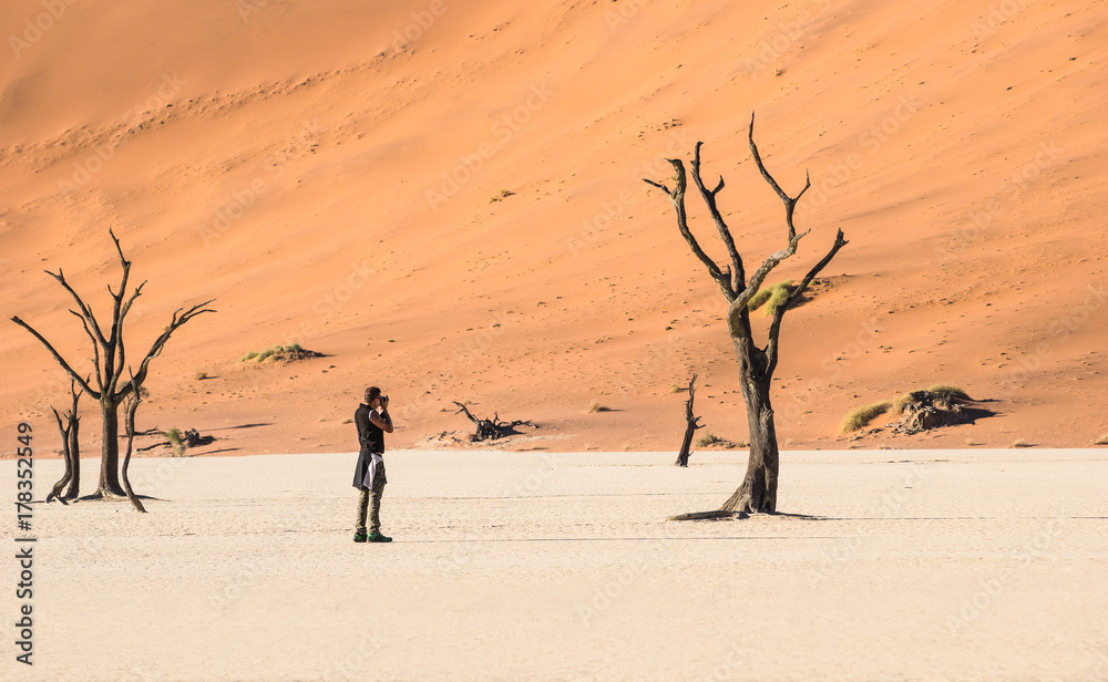 Lonely adventure travel photographer at Deadvlei crater in Sossusvlei territory - Namibian world famous desert - Wander concept with african nature wonder with unique wild landscape in Namibia