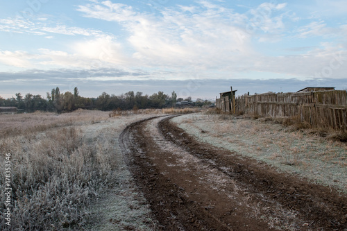 The road is on the outskirts of the village. The first hoarfrost. Sunrise.