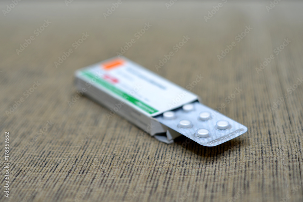 Fototapeta premium White pills spilling out of a toppled bright red orange pill bottle