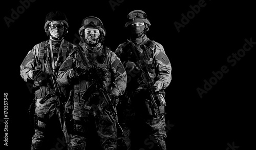 Three soldiers in uniform with a weapon in their hands are looking menacingly. photo