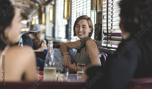 Smiling woman sitting with two friends in a booth in a diner.