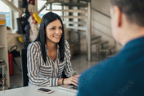 Woman talking with client in car shop.
