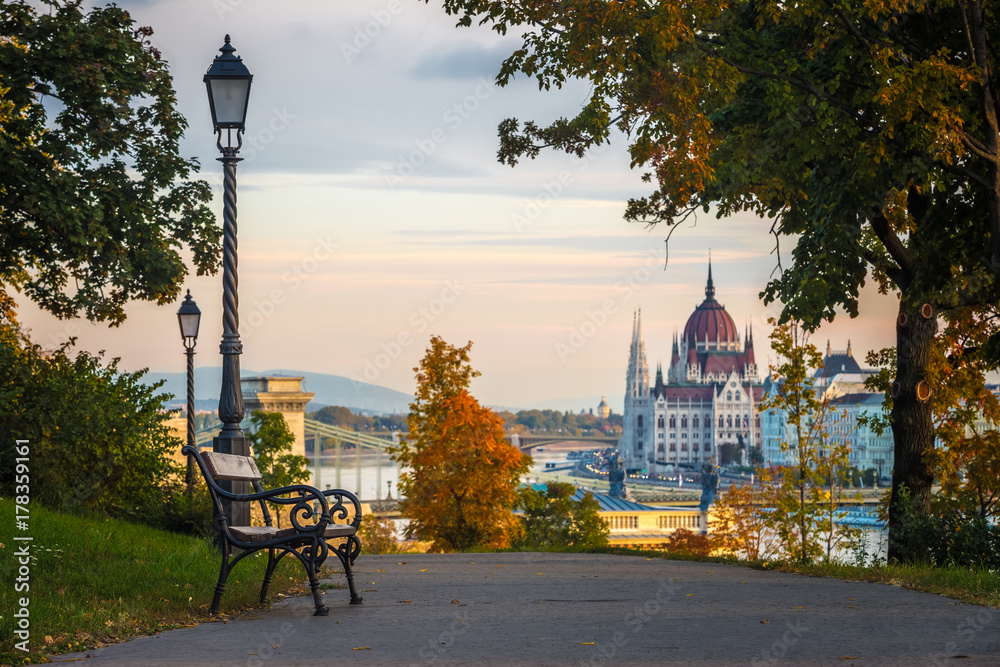 Fototapeta premium Budapeszt, Węgry - ławka i jesienne liście na wzgórzu Buda z węgierskim parlamentem i mostem łańcuchowym w tle