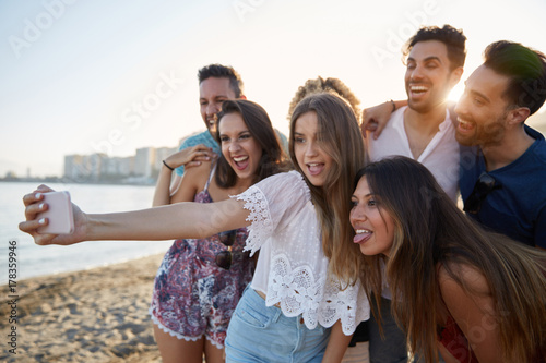 Pretty girl taking selfie with friends on beach © innervisionpro