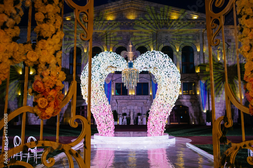 Wedding altar made of flower archs stands on the backyard in the evening