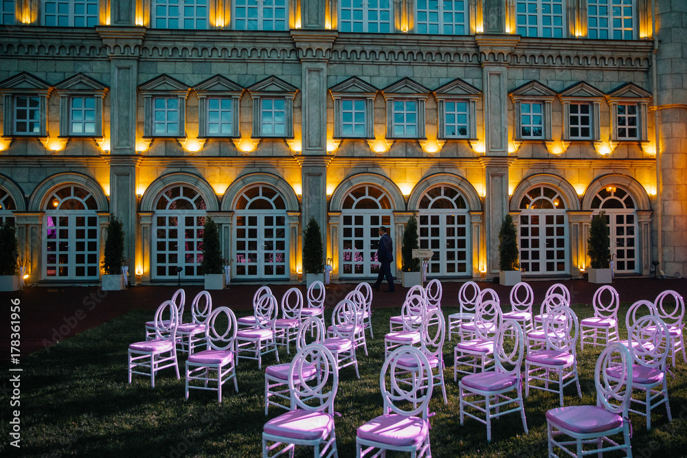White chairs with pink seats stand on the backyard
