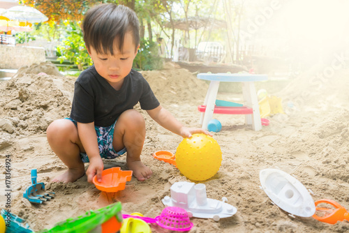 cute asian boy plays with sand on summer day
