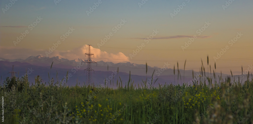 Mountains, sunset sky, summer field and high voltage tower, Kazakhstan