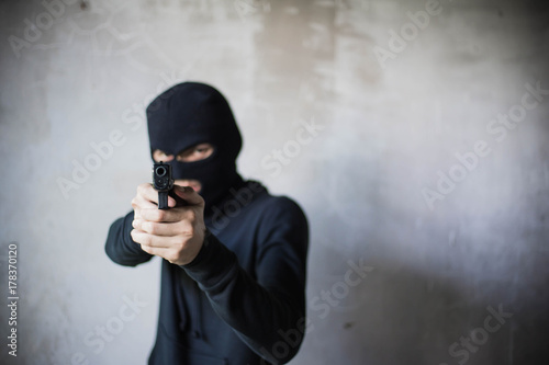Terrorist or gunman wearing a mask and holding a gun ready to fire
