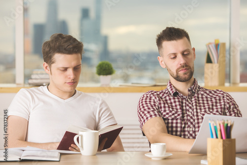 Attractive businessmen reading book and doing paperwork