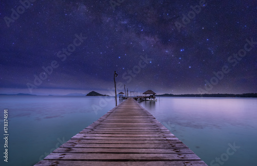 night view of ocean wood dock and milkyway on sky