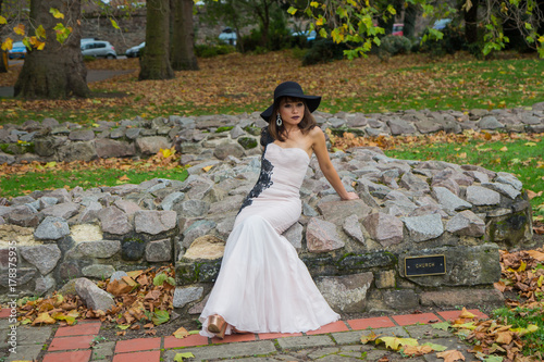 Filipino female model at Autumn time in a park during the daytime, with lush foliage all around.