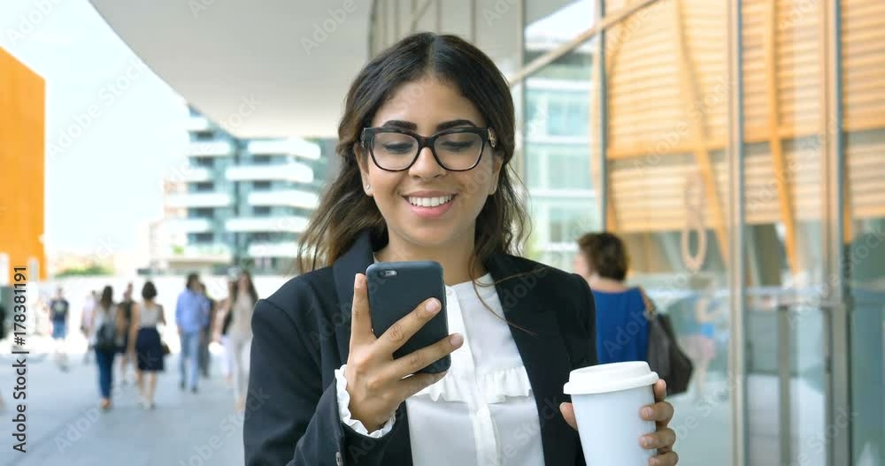 Portrait of a young beautiful business woman (student) in a suit, glasses, walking around the city, drinking coffee, talking on the phone. Concept: new business, communication, Arab, banker, manager. Portrait of a young beautiful business woman (student) in a suit, glasses, walking around the city, drinking coffee, talking on the phone. Concept: new business, communication, Arab, banker, manager.