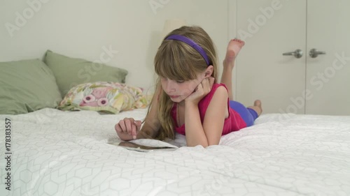 Girl lying in bed and using a tablet