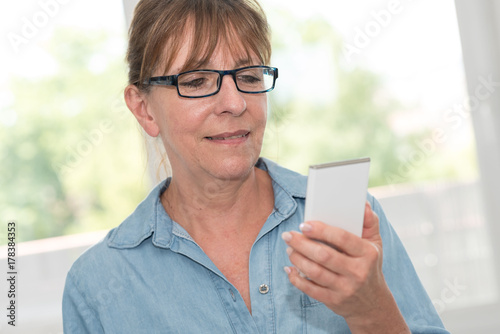 Mature woman using her mobile phone, light effect