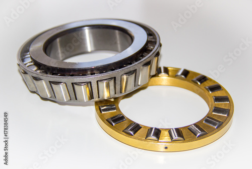 Brass roller cage of a thrust roller bearing and stainless roller cage of a tapered roller bearing with selective focus