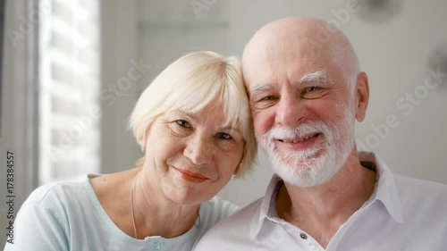 Portrait of happy senior couple at home. Senior man expresses his emotions and kisses his wife. Very emotional moment. Happy family enjoying time together.