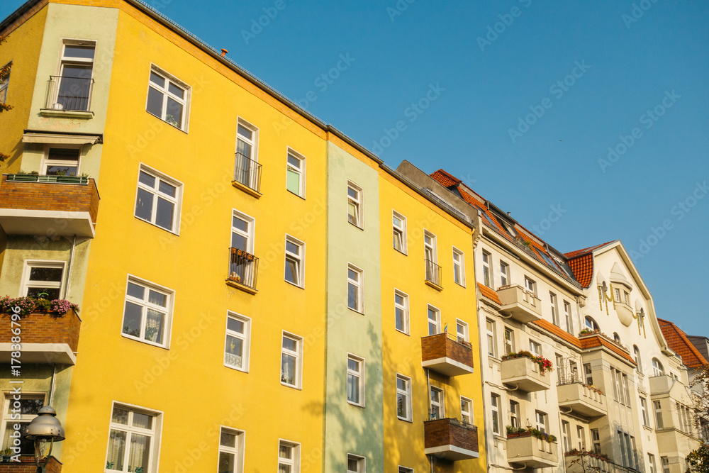 colorful yellow house next to an white facaded apartment building